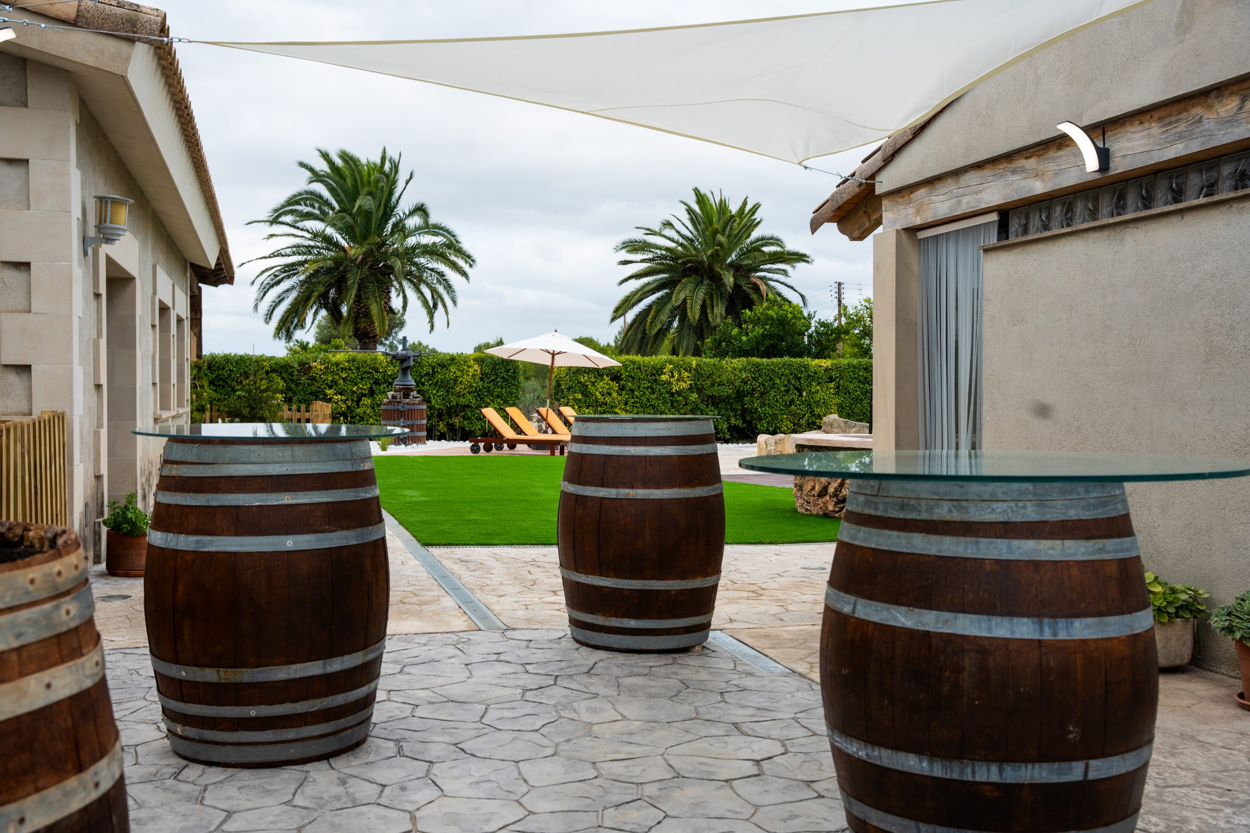 Taules fetes amb bótes de vi davant el jardí i zona de piscina a la Masia L’Encís