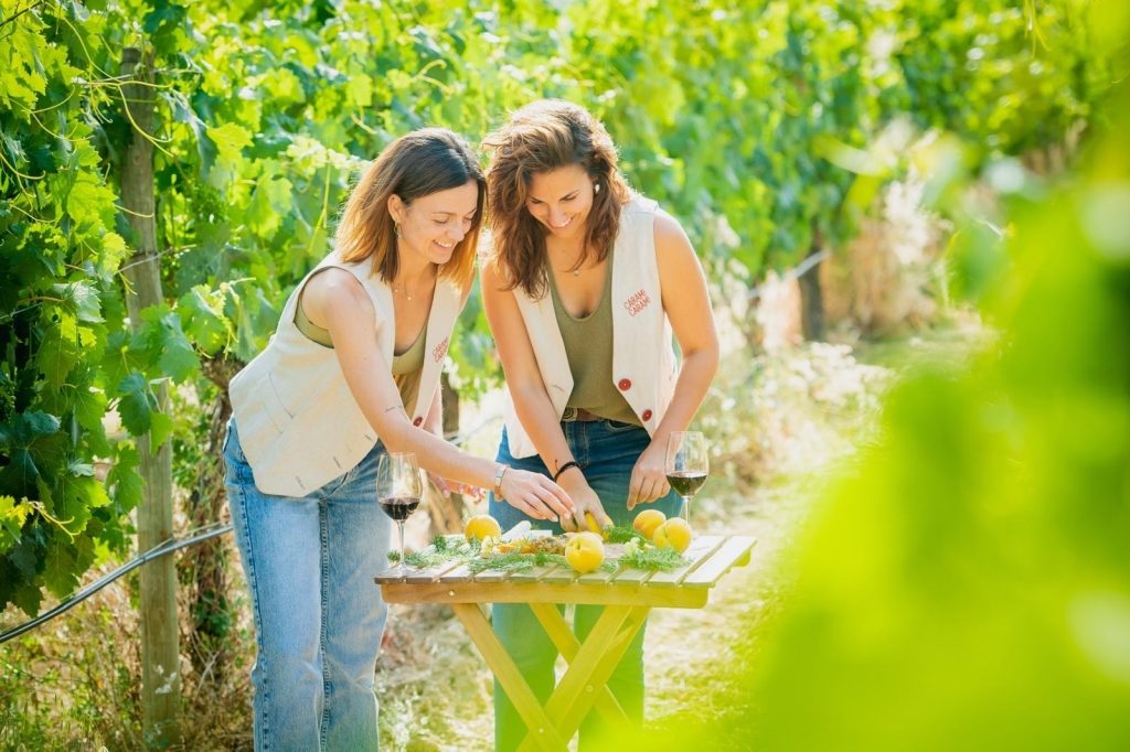 Dues dones gaudint d’una experiència enoturística entre vinyes a la Masia L’Encís