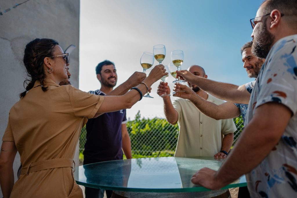 Grup de persones brindant amb vi blanc en una celebració a Masia L’Encís