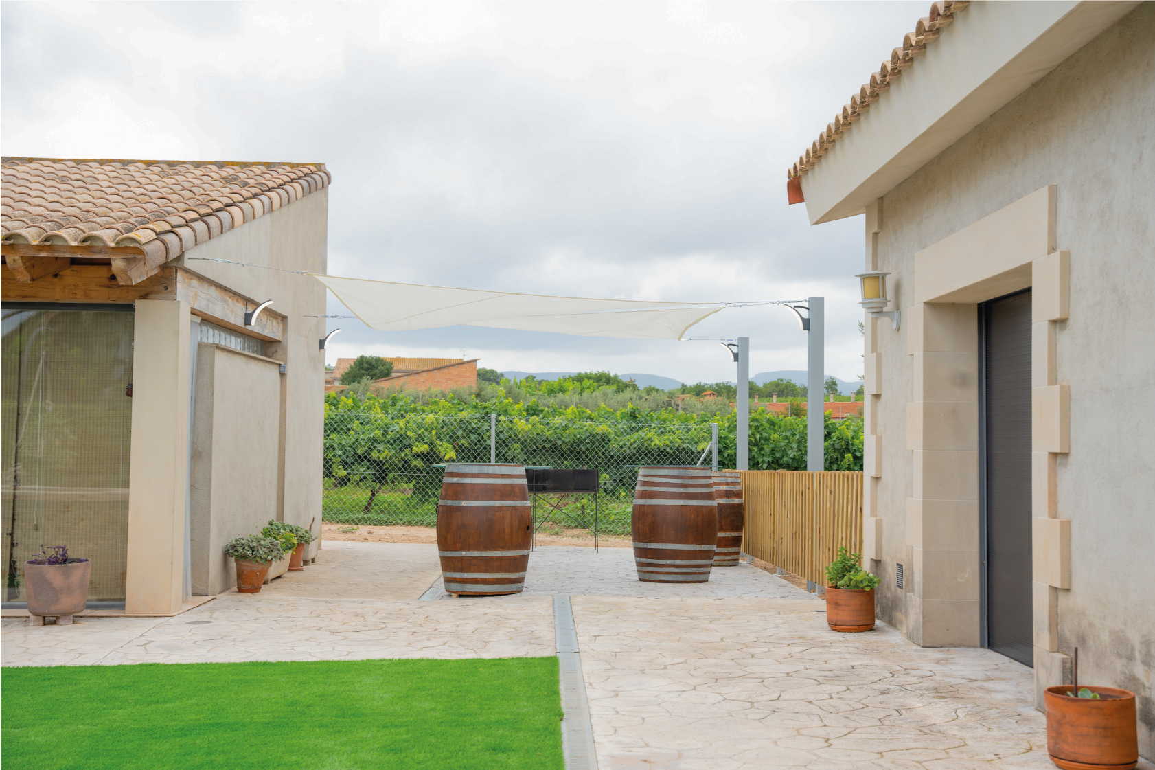 Zona exterior amb botes de fusta i vistes a les vinyes a la Masia L’Encís