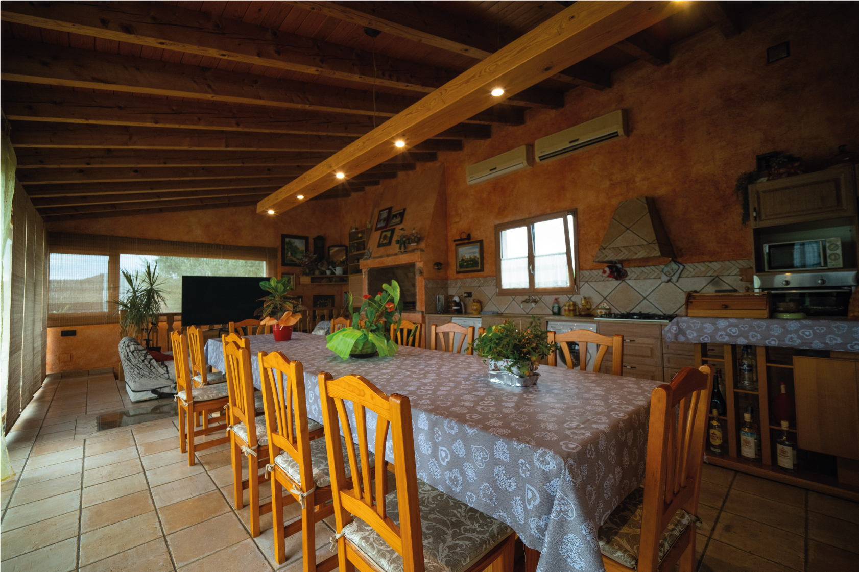 Cuina menjador interior de la Masia L’Encís amb taula gran, decoració rústica i sostre de fusta