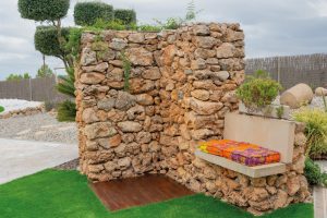 Dutxa exterior de pedra amb banc integrat al jardí de la Masia L’Encís