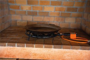 Paeller tradicional amb fogó de gas a la Masia L’Encís, sobre base de rajoles rústiques