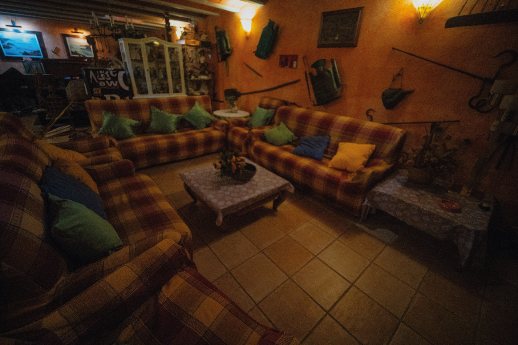 Sala d’estar rústica de la Masia L’Encís amb sofàs, coixins de colors i decoració tradicional