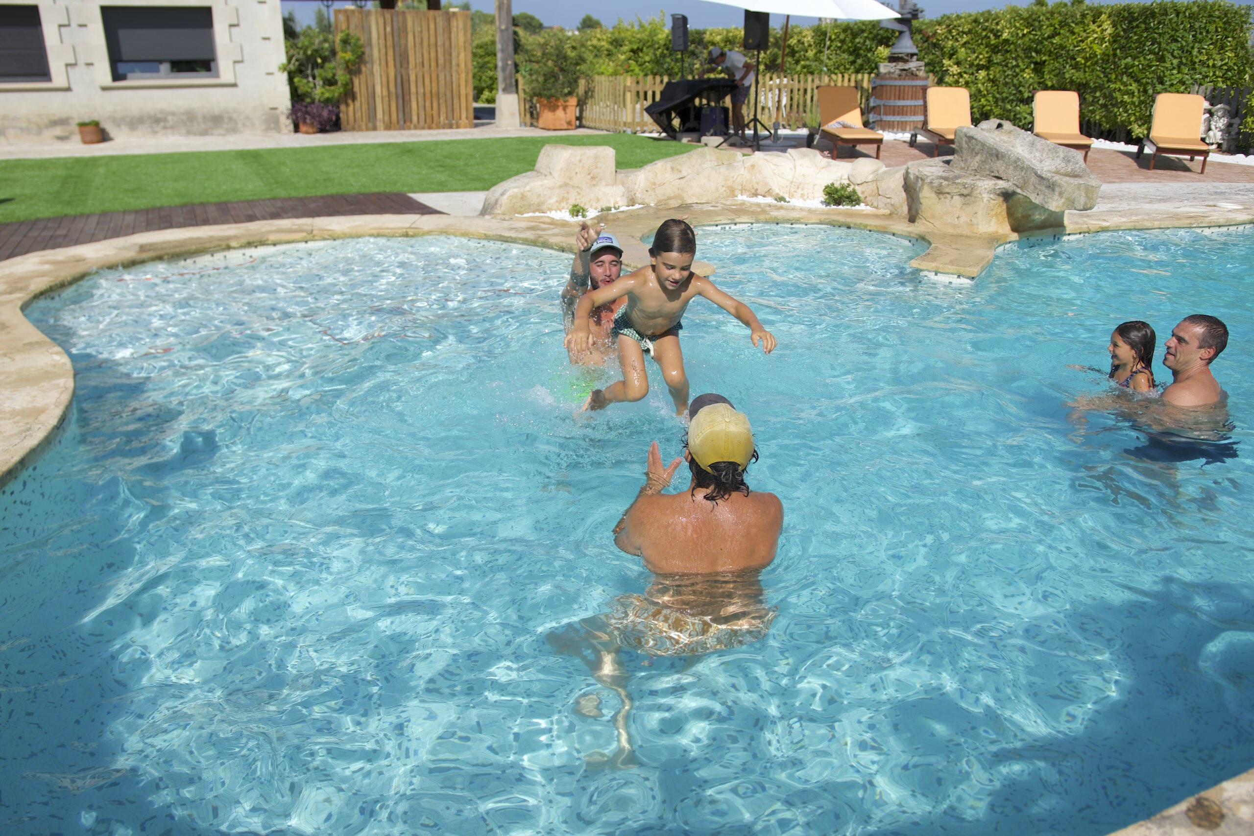 Nens saltant a la piscina mentre juguen amb la família a la Masia L’Encís en un dia d’estiu