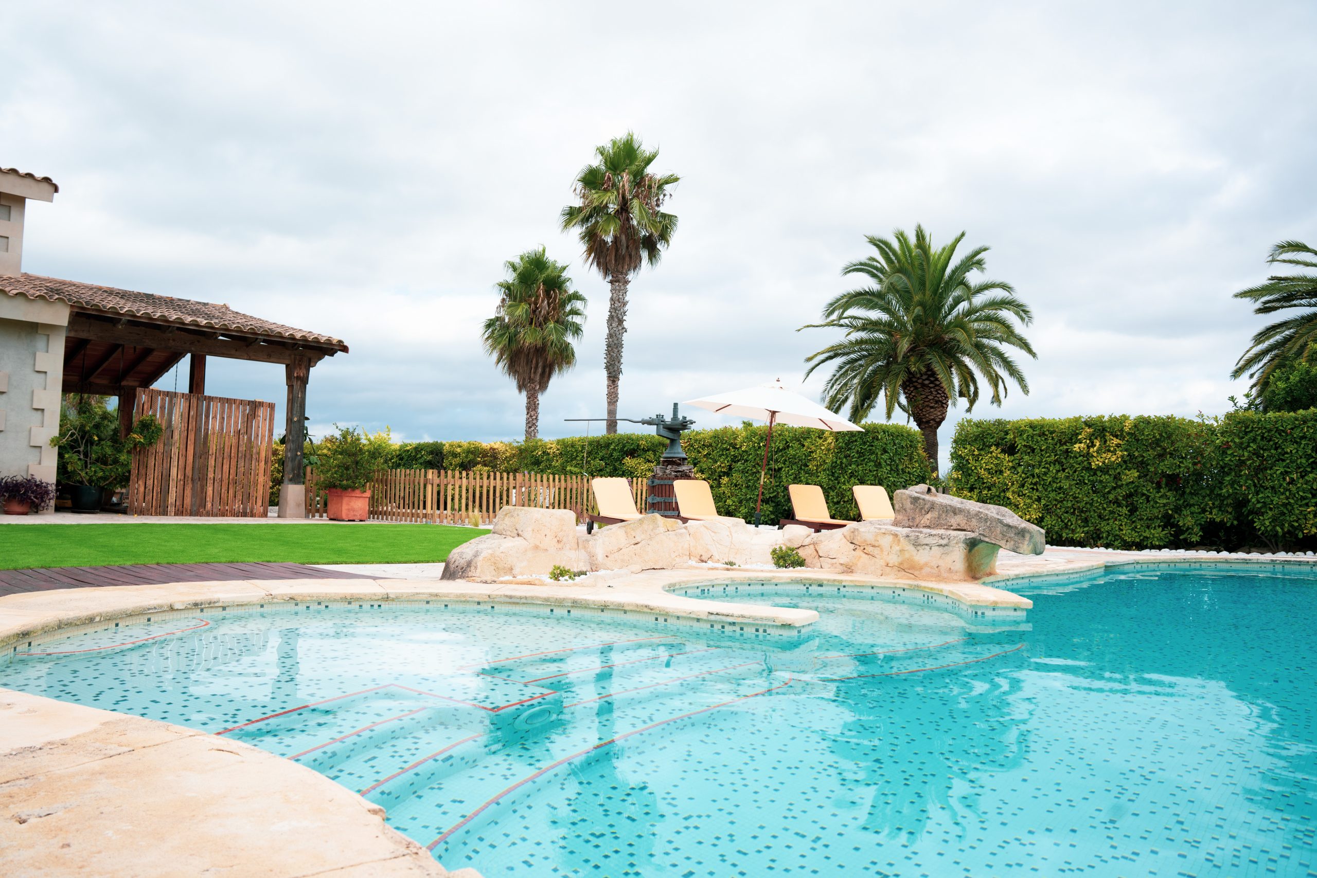 Piscina exterior amb gandules i palmeres a la Masia L’Encís