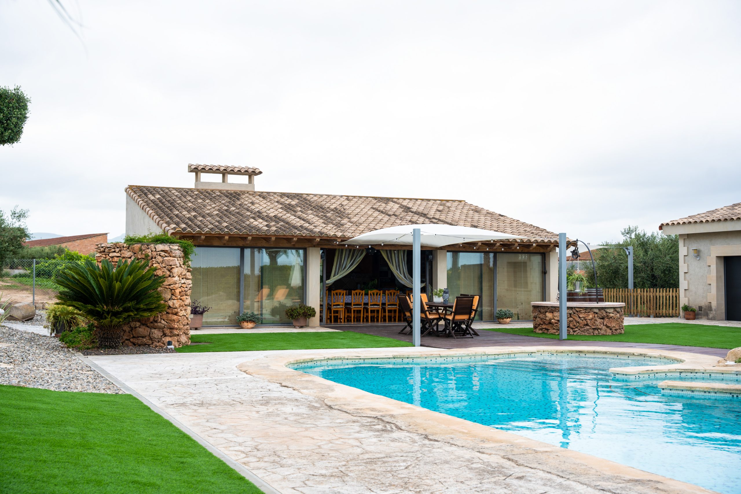 Vista de la Masia L’Encís amb piscina i porxo amb taula de fusta
