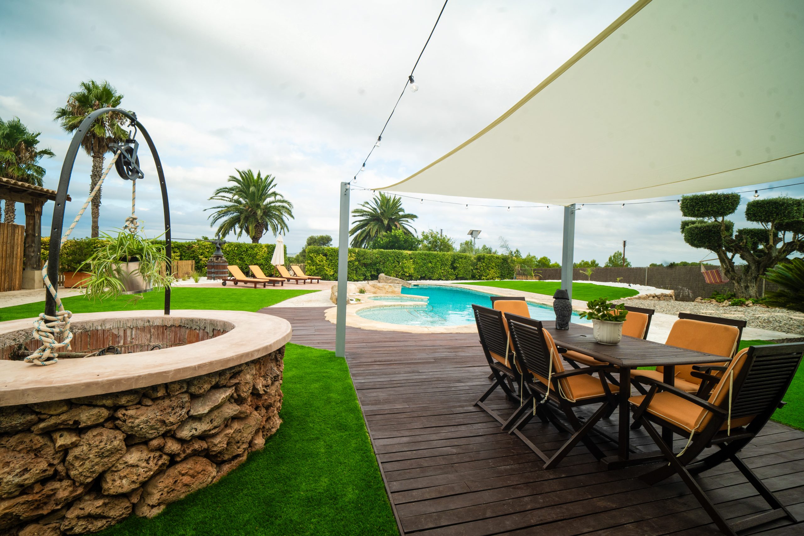 Zona chill-out amb taula i cadires davant la piscina a la Masia L’Encís